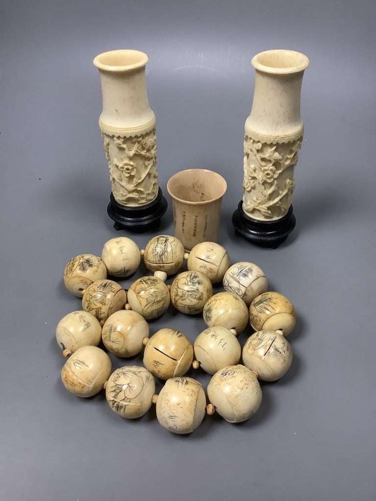 A Chinese engraved bone bead necklace, a pair of engraved bone vases on stands and an engraved bone dice shaker